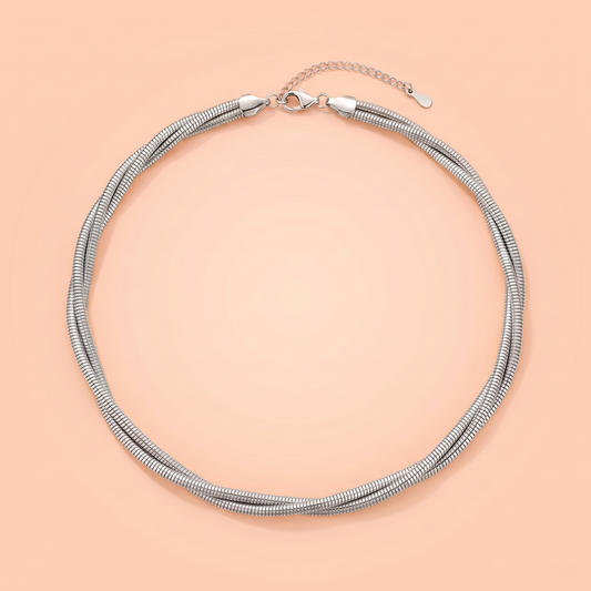Treccia Choker in silver laid flat on a peach background
