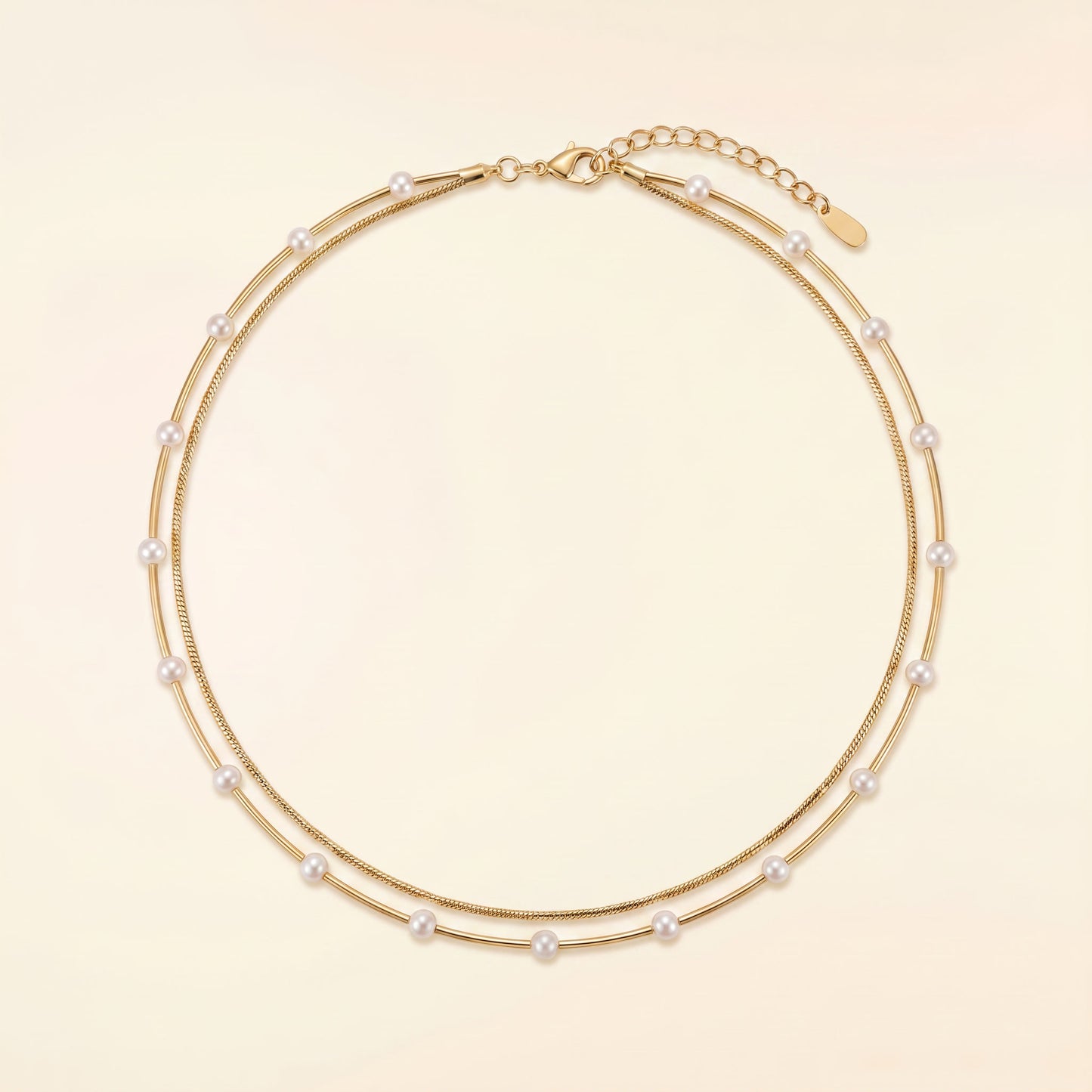 A double-strand gold chain necklace adorned with small white pearls, displayed on a light beige background.