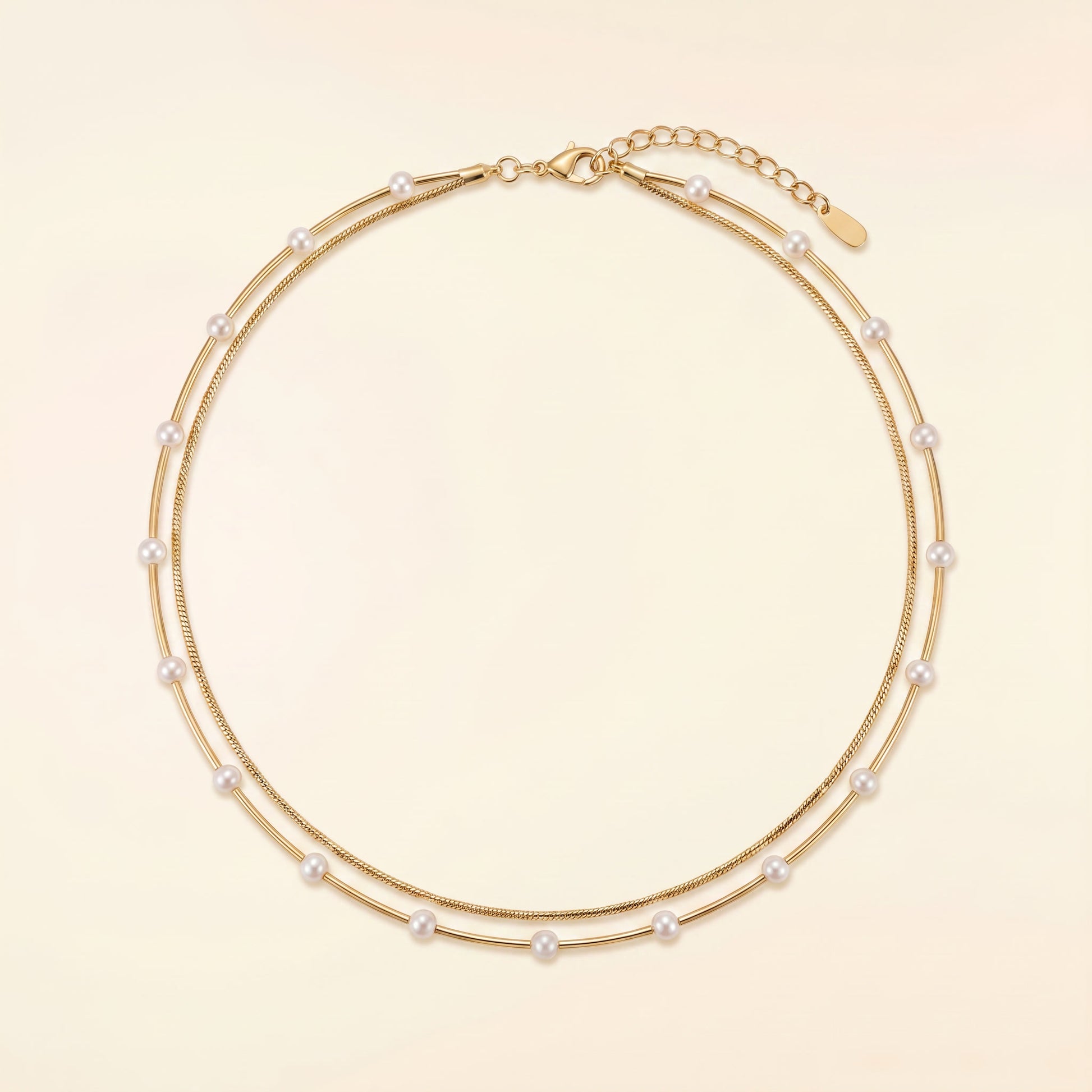 A double-strand gold chain necklace adorned with small white pearls, displayed on a light beige background.
