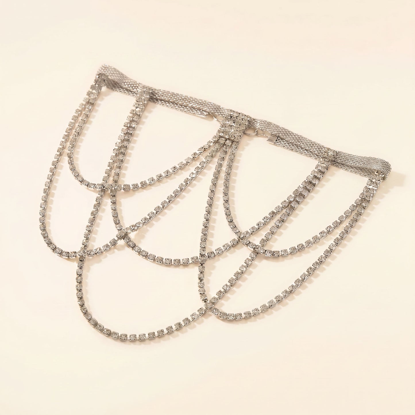 A silver-toned rhinestone chain choker with multiple draped loops, displayed on a plain light beige background.