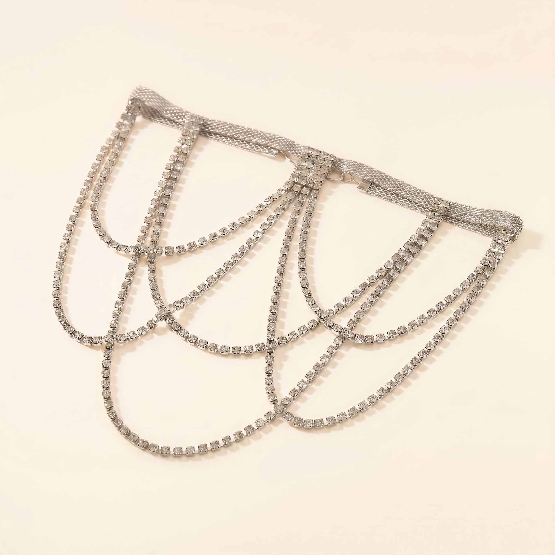 A silver-toned rhinestone chain choker with multiple draped loops, displayed on a plain light beige background.