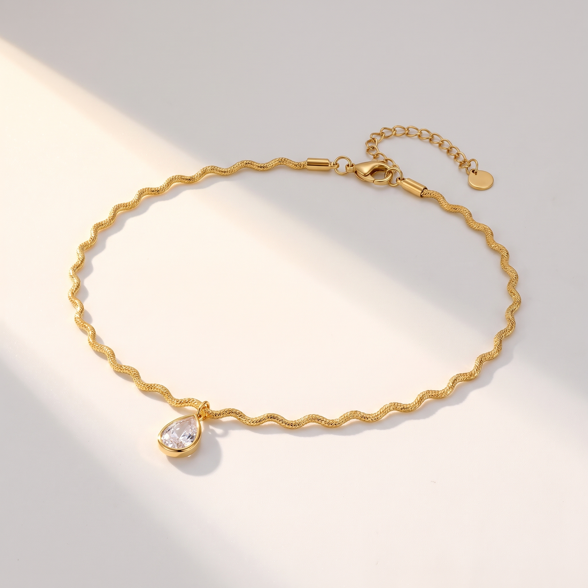 Onda Choker in gold on a white surface in soft sunlight
