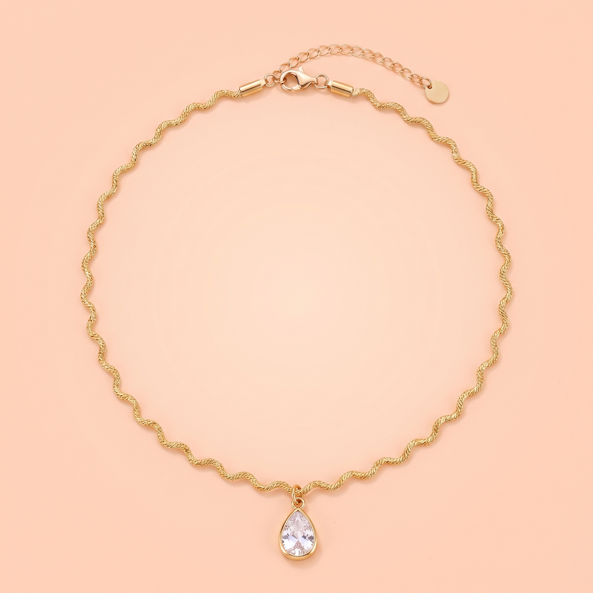Onda Choker in gold laid flat on a peach background