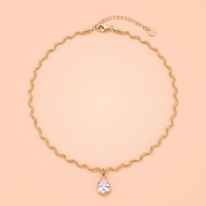 Onda Choker in gold laid flat on a peach background