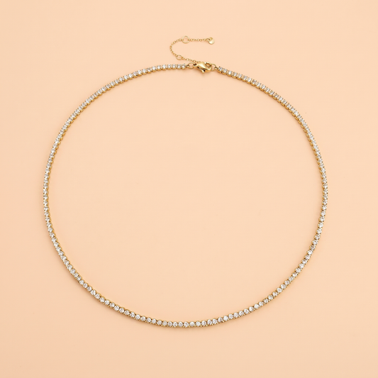 Filo Choker in gold laid flat on a peach background