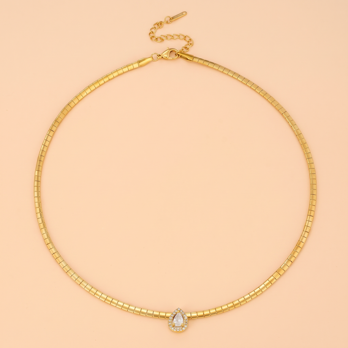 Aura Choker in gold laid flat on a peach background