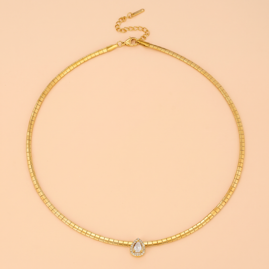 Aura Choker in gold laid flat on a peach background