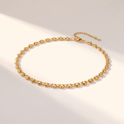 Cuori Choker in gold on a white surface in soft sunlight