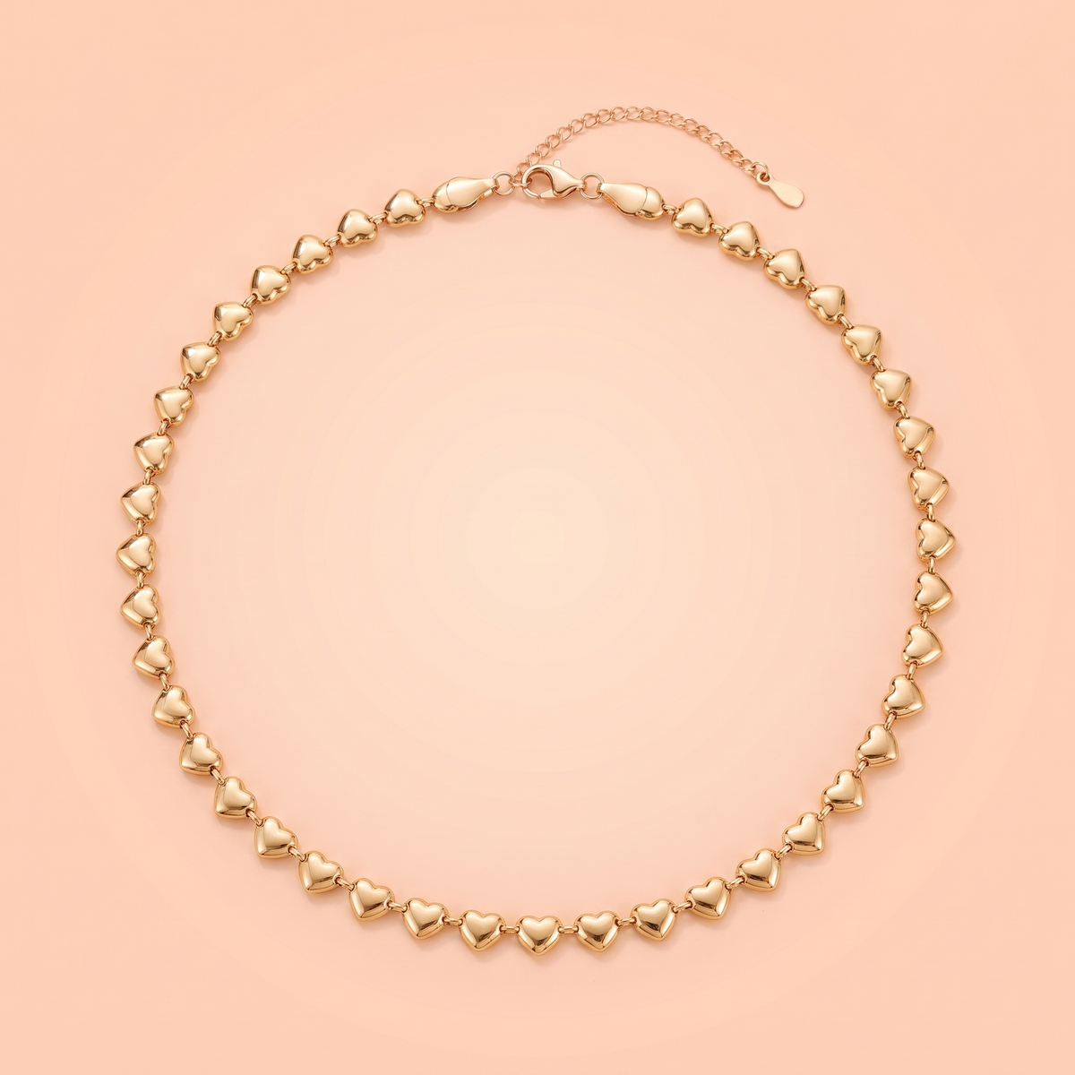 Cuori Choker in gold laid flat on a peach background