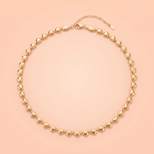 Cuori Choker in gold laid flat on a peach background