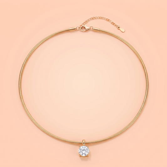 Unica Choker in gold laid flat on a peach background