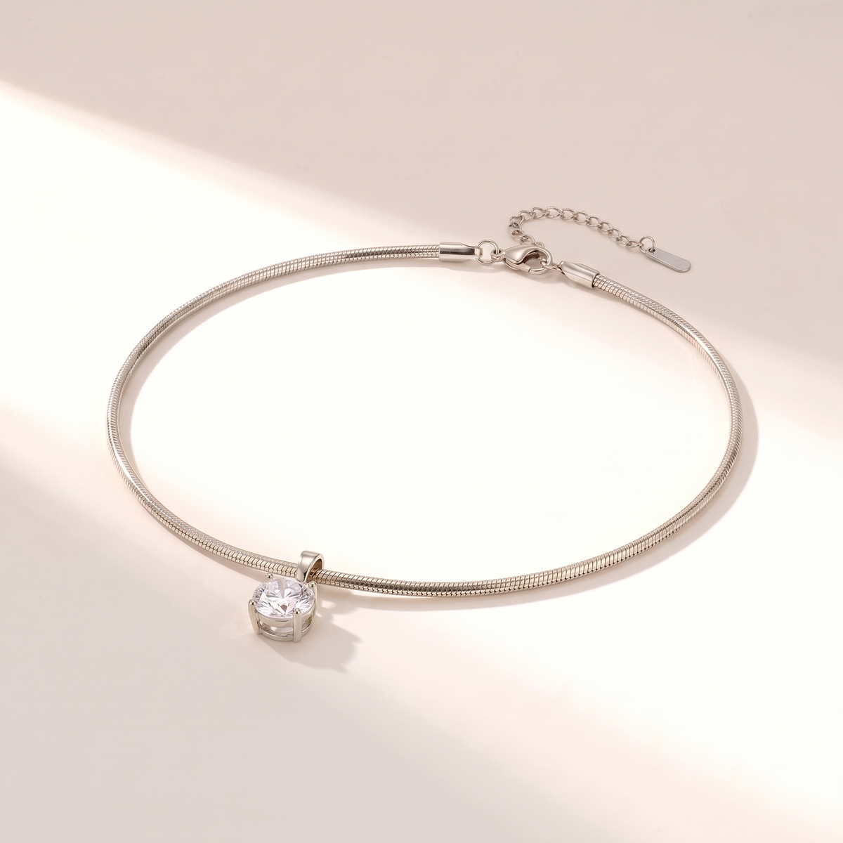 Unica Choker in silver on a white surface in soft sunlight