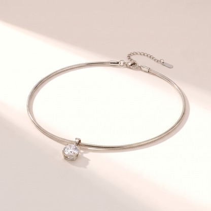 Unica Choker in silver on a white surface in soft sunlight