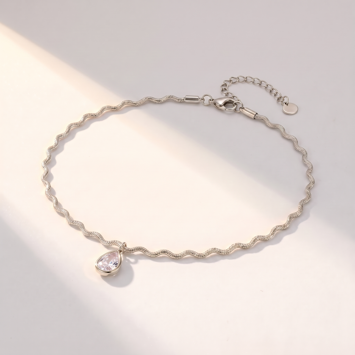 Onda Choker in silver on a white surface in soft sunlight