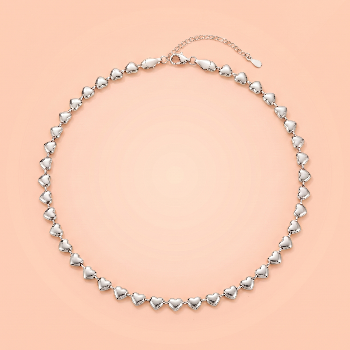 Cuori Choker in silver laid flat on a peach background