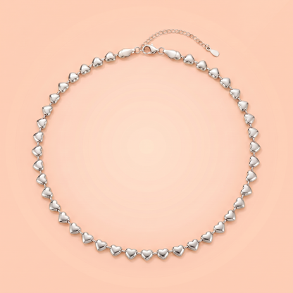 Cuori Choker in silver laid flat on a peach background