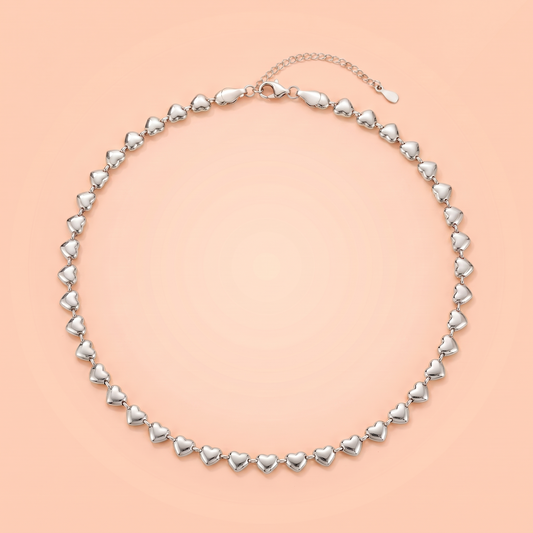 Cuori Choker in silver laid flat on a peach background