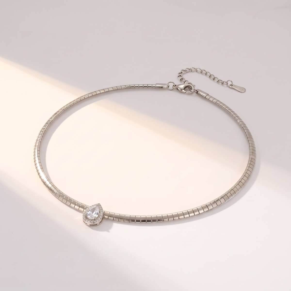 Aura Choker in silver on a white surface in soft sunlight