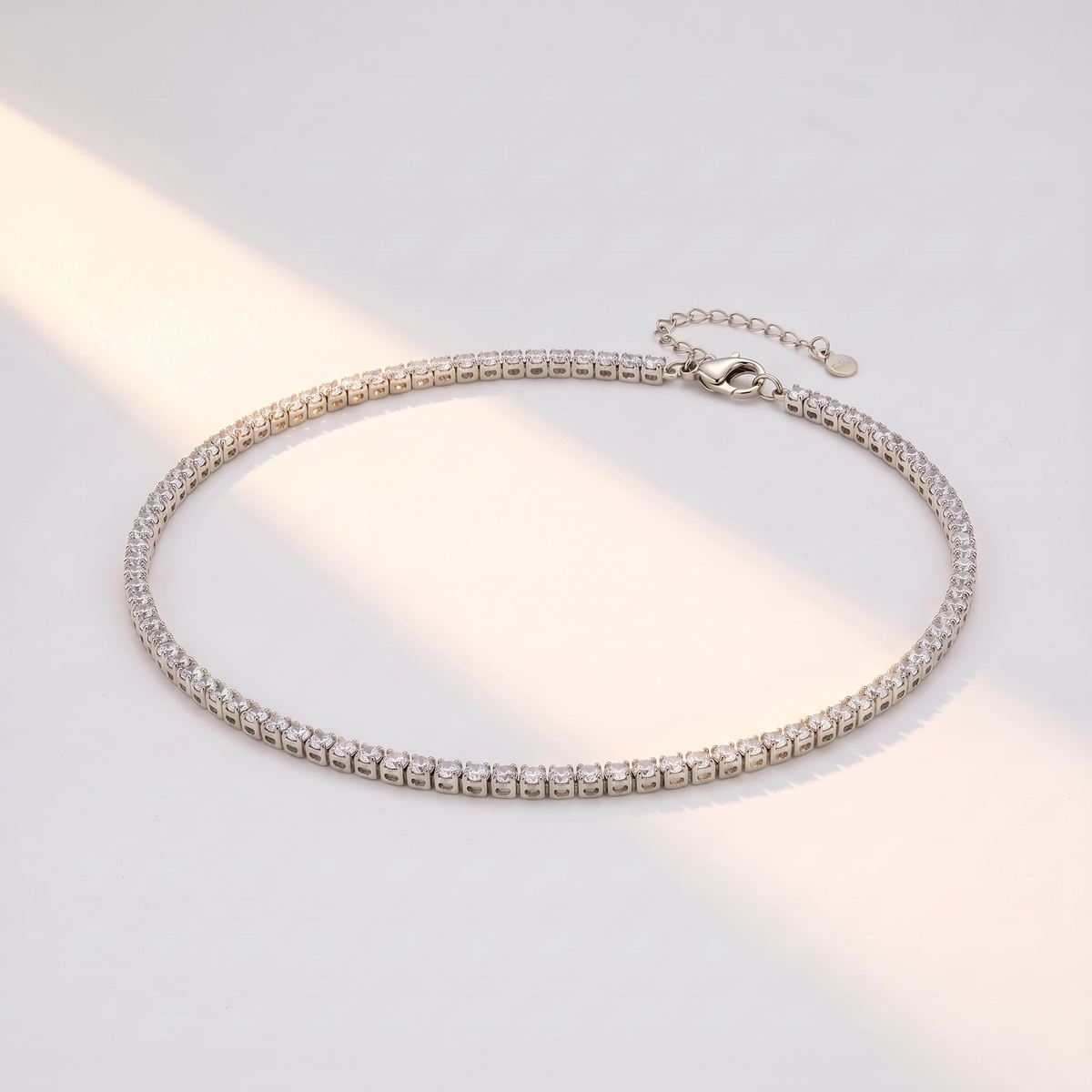 Filo Choker in silver on a white surface in soft sunlight