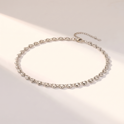 Cuori Choker in silver on a white surface in soft sunlight