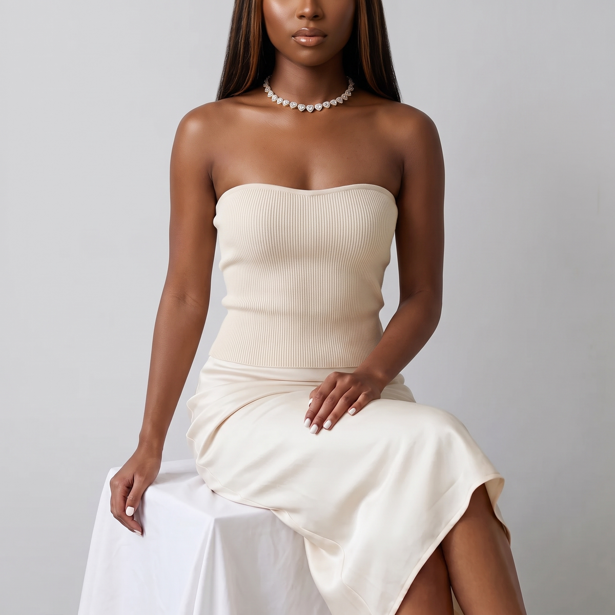 Model seated in a cream knit top wearing the Amore Choker in gold