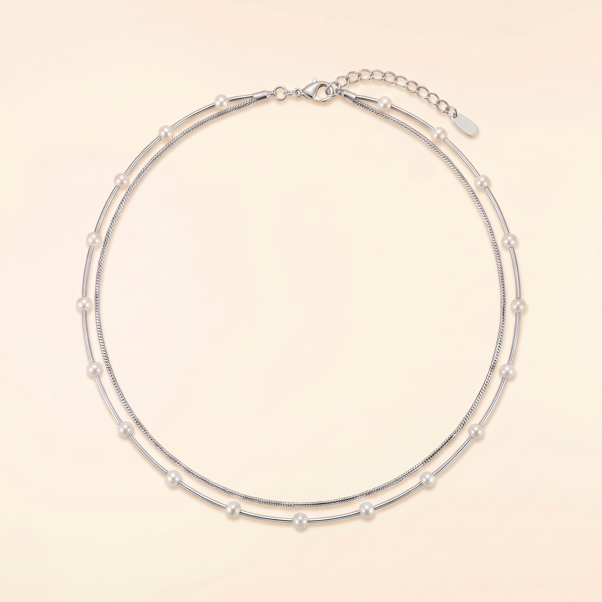A double-strand silver chain necklace adorned with small white pearls, displayed on a light beige background.